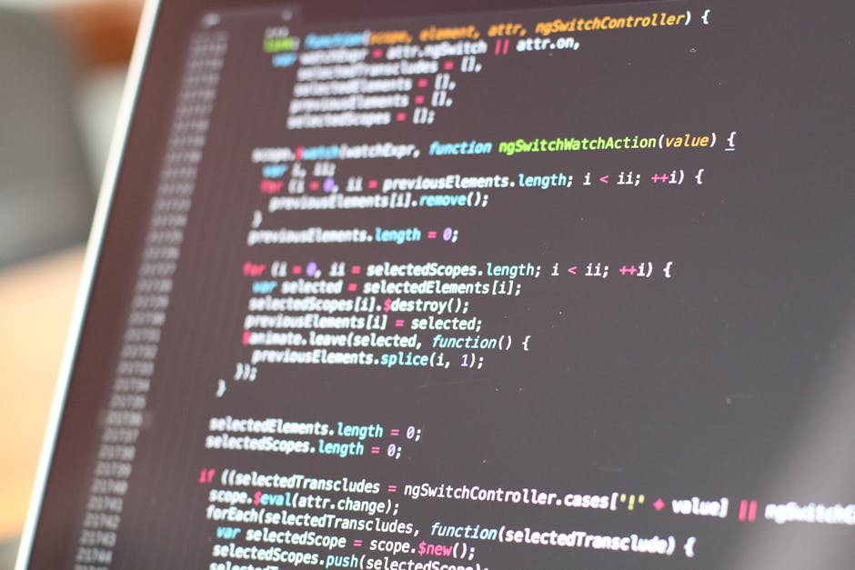 The image displays a close-up view of a computer screen filled with lines of colorful programming code with syntax highlighting, including elements in blue, orange, green, yellow, and red. Part of the